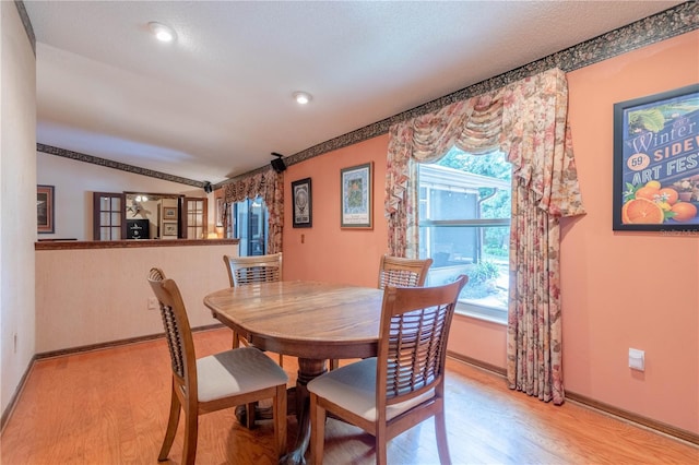 dining area with light hardwood / wood-style flooring and vaulted ceiling