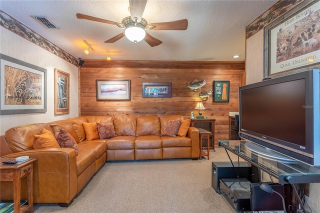 carpeted living room with wooden walls, rail lighting, a textured ceiling, and ceiling fan