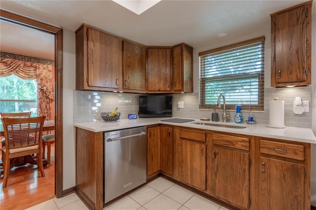 kitchen featuring tasteful backsplash, sink, light tile patterned floors, and stainless steel dishwasher