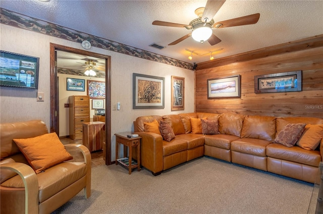 carpeted living room with wood walls, track lighting, a textured ceiling, and ceiling fan