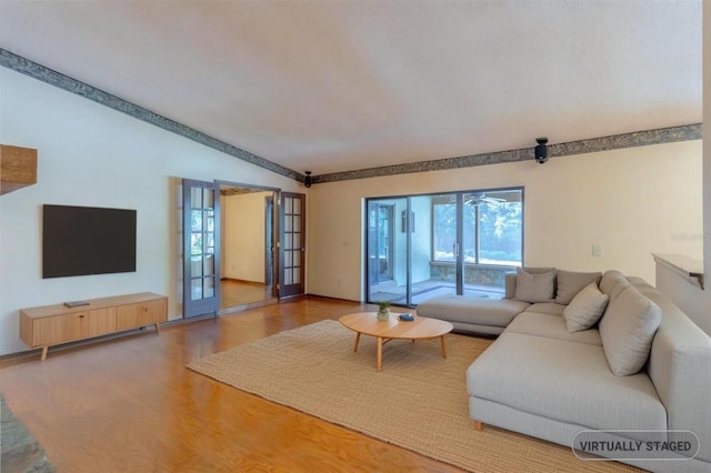 living area with lofted ceiling, wood finished floors, and french doors