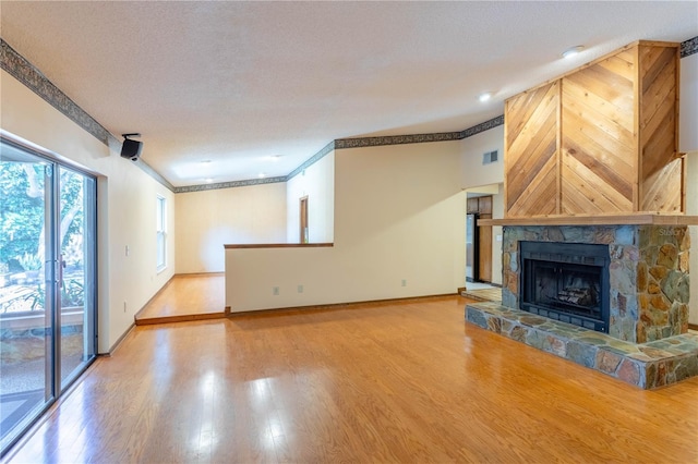 unfurnished living room featuring a fireplace, wood finished floors, visible vents, and baseboards