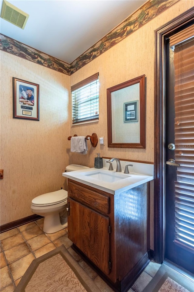 bathroom with toilet, vanity, visible vents, and wallpapered walls