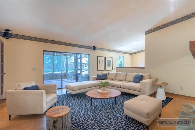 living area with ornamental molding, wood finished floors, and baseboards