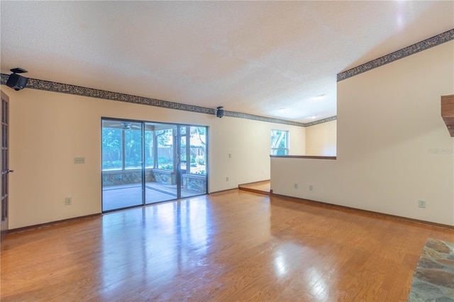 unfurnished living room with a healthy amount of sunlight, a textured ceiling, and wood finished floors