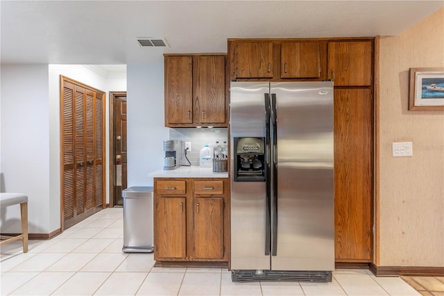 kitchen featuring light tile patterned floors, light countertops, brown cabinetry, and stainless steel fridge