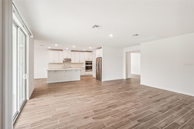 unfurnished living room with sink and light hardwood / wood-style floors