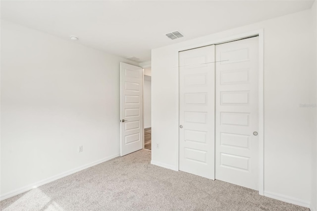 unfurnished bedroom featuring light colored carpet and a closet