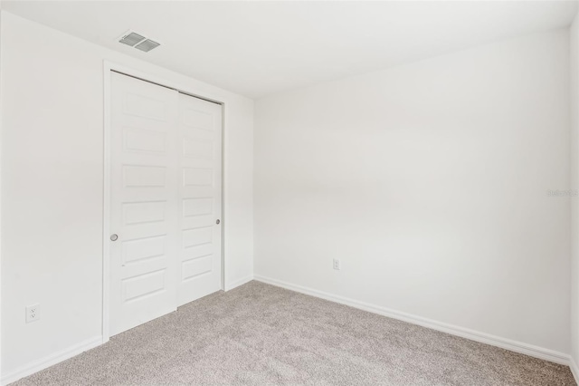 unfurnished bedroom featuring light colored carpet and a closet