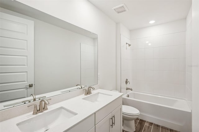 full bathroom with vanity, tiled shower / bath combo, hardwood / wood-style flooring, and toilet