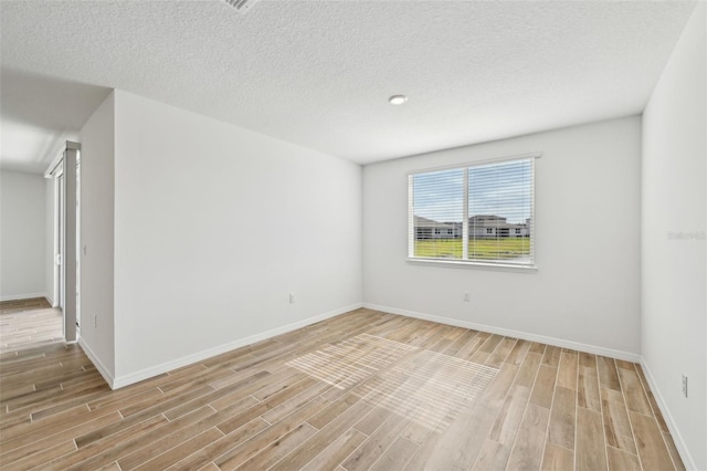 unfurnished room with light hardwood / wood-style floors and a textured ceiling