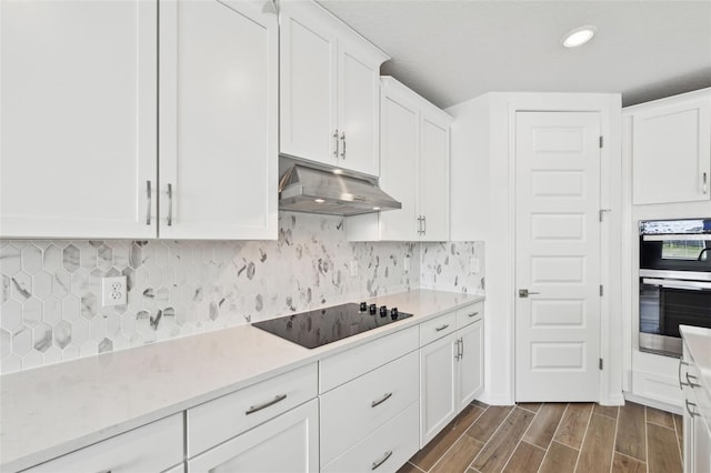 kitchen with stainless steel double oven, white cabinets, tasteful backsplash, and black electric cooktop