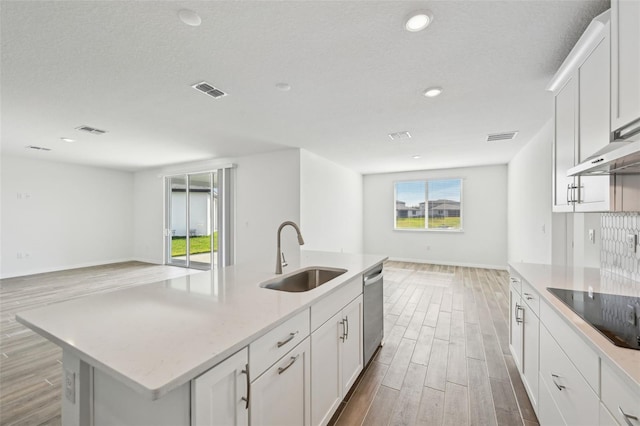 kitchen with stainless steel dishwasher, black electric cooktop, a kitchen island with sink, white cabinets, and sink