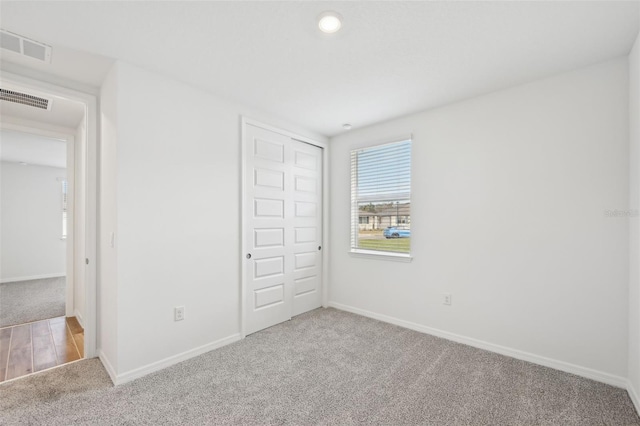 unfurnished bedroom with a closet and light carpet