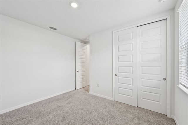 unfurnished bedroom with a closet and light carpet