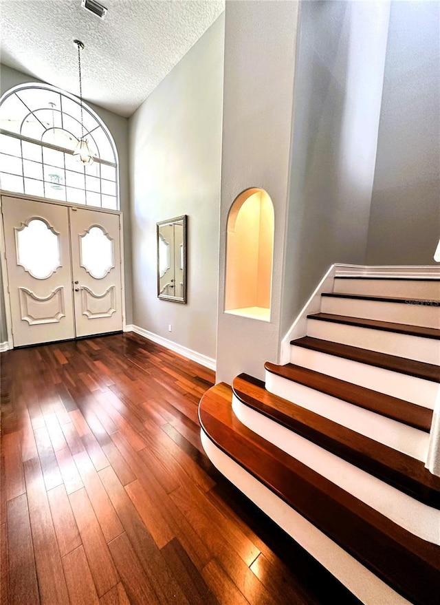 foyer entrance featuring dark wood-type flooring, a textured ceiling, and a notable chandelier