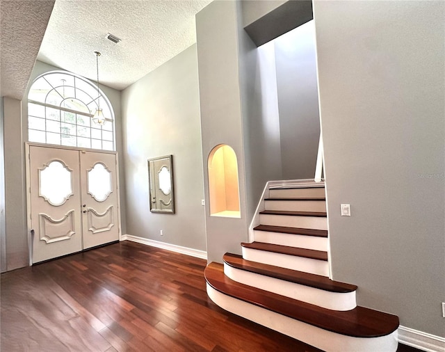 foyer entrance featuring dark hardwood / wood-style floors, an inviting chandelier, and a textured ceiling