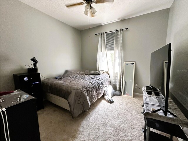 carpeted bedroom featuring ceiling fan and a textured ceiling