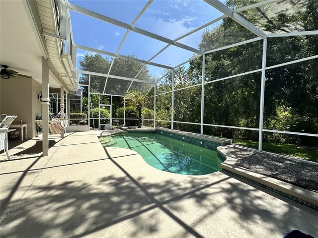 view of swimming pool with glass enclosure and a patio