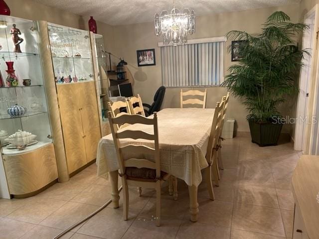 dining space featuring light tile patterned flooring, a textured ceiling, and a notable chandelier