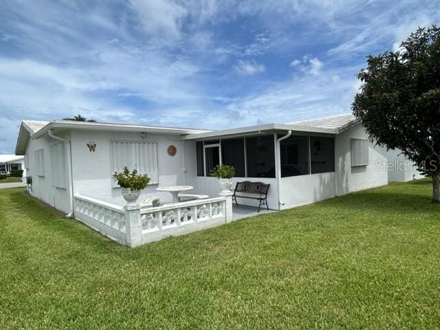 back of property with a sunroom and a yard