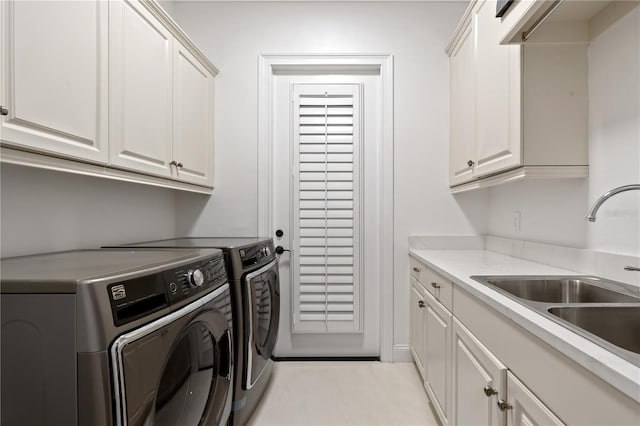 clothes washing area with cabinets, sink, and washing machine and clothes dryer