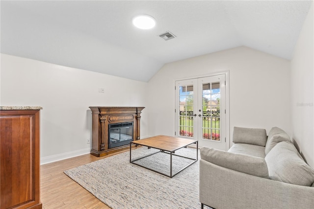 living room with lofted ceiling, french doors, and light wood-type flooring