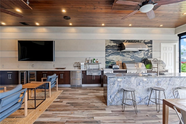 kitchen with light hardwood / wood-style floors, wooden ceiling, backsplash, wall chimney range hood, and stone counters