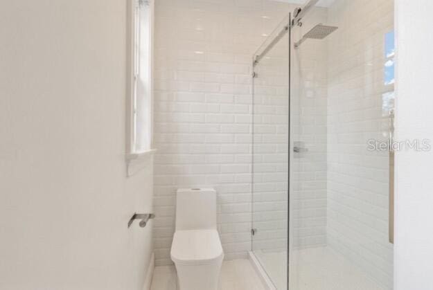 bathroom featuring toilet and an enclosed shower