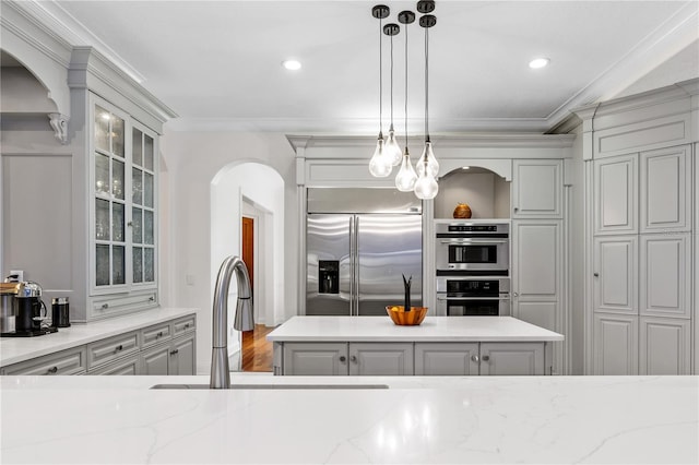 kitchen with decorative light fixtures, crown molding, stainless steel appliances, and a kitchen island