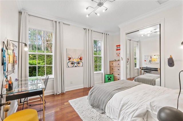 bedroom with wood-type flooring, multiple windows, a closet, and crown molding