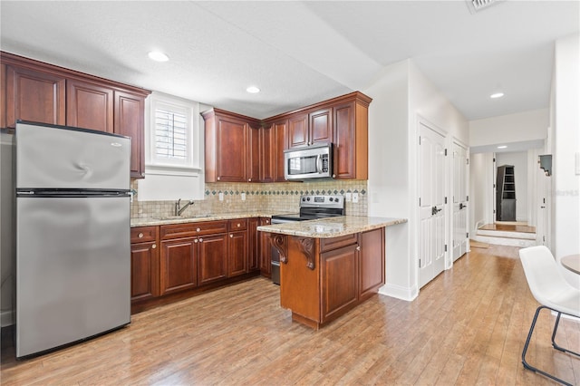 kitchen featuring light stone countertops, stainless steel appliances, decorative backsplash, sink, and light hardwood / wood-style flooring