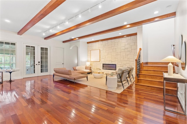 living room with french doors, beamed ceiling, a stone fireplace, and wood-type flooring