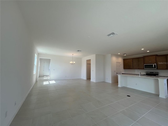 unfurnished living room with light tile patterned flooring, a notable chandelier, and sink