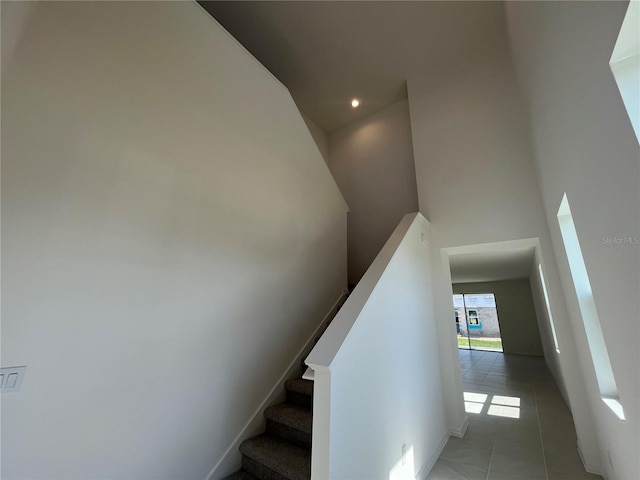 staircase with a towering ceiling and tile patterned floors