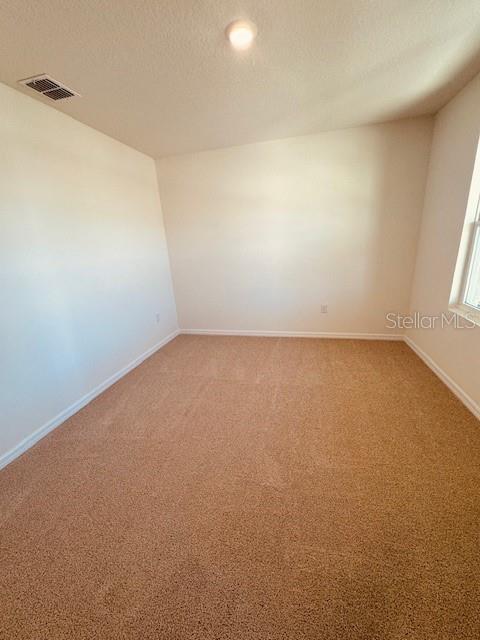 carpeted empty room with a textured ceiling