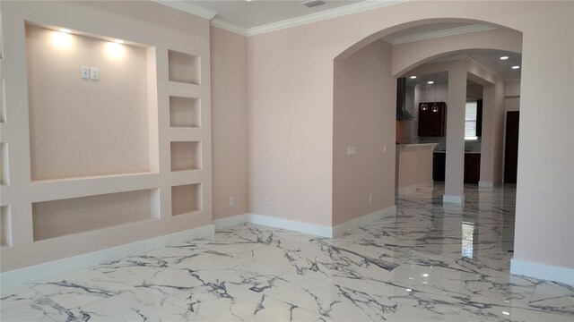 empty room with ornamental molding and built in features