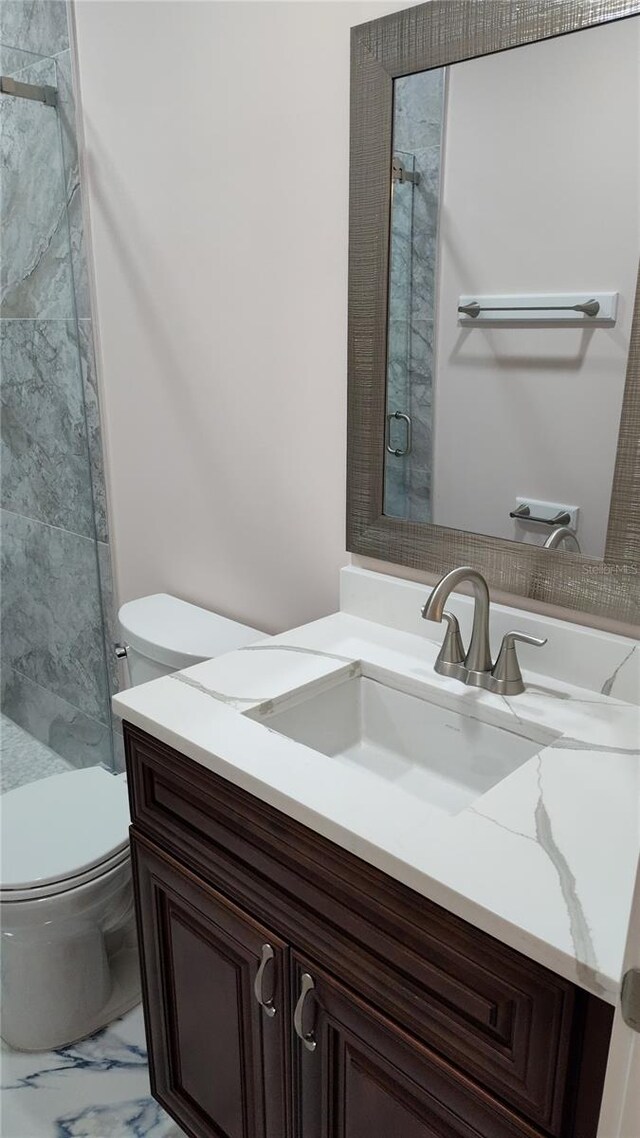 bathroom with vanity, toilet, and a shower with door