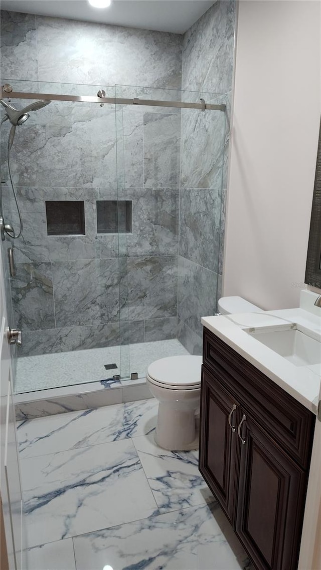 bathroom with vanity, toilet, and a shower with door