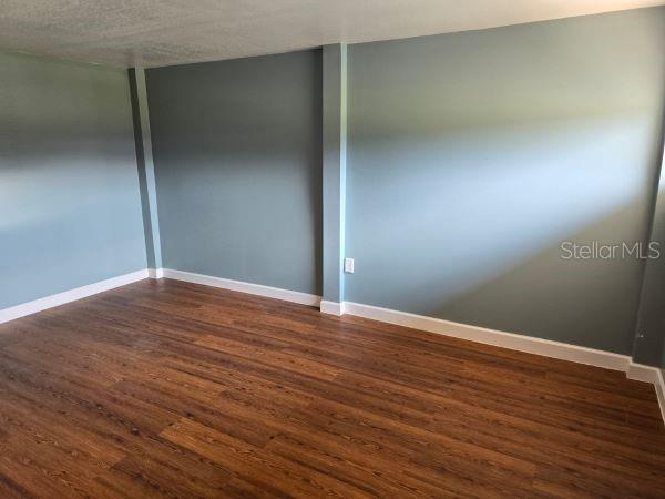 unfurnished room featuring dark hardwood / wood-style flooring and a textured ceiling