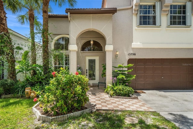 property entrance featuring an attached garage, driveway, and stucco siding