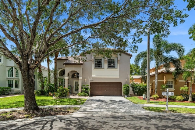 mediterranean / spanish-style home with stucco siding, driveway, a front yard, and an attached garage