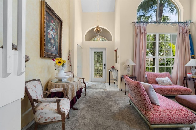 sitting room featuring an inviting chandelier, carpet, and a towering ceiling