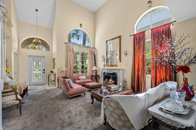 living area featuring high vaulted ceiling, a fireplace, a chandelier, and carpet flooring