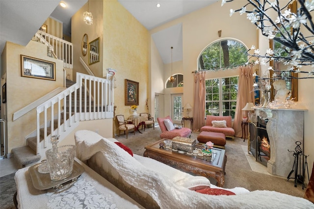 living room with stairway, a fireplace with flush hearth, a high ceiling, and carpet floors