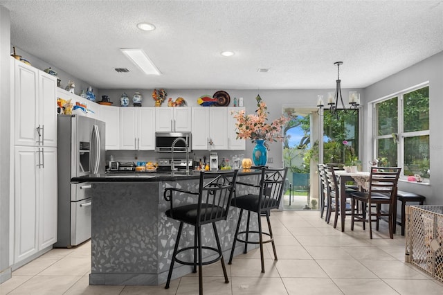 kitchen featuring a breakfast bar area, an inviting chandelier, stainless steel appliances, white cabinetry, and dark countertops