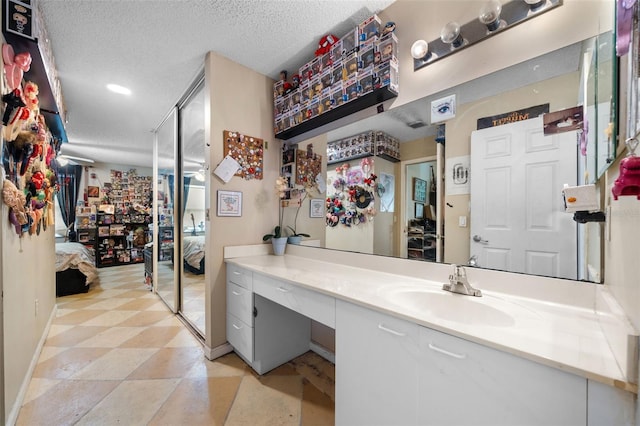 bathroom featuring vanity, baseboards, ensuite bathroom, and a textured ceiling