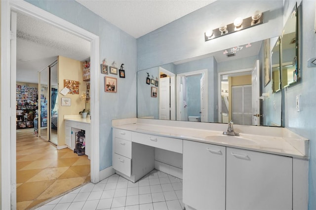 full bathroom with vanity, toilet, tile patterned flooring, and a textured ceiling