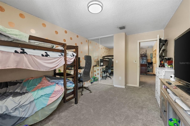 carpeted bedroom featuring visible vents, a textured ceiling, a closet, wallpapered walls, and baseboards