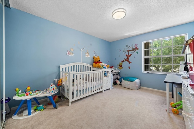 bedroom featuring baseboards, a textured ceiling, a nursery area, and carpet floors